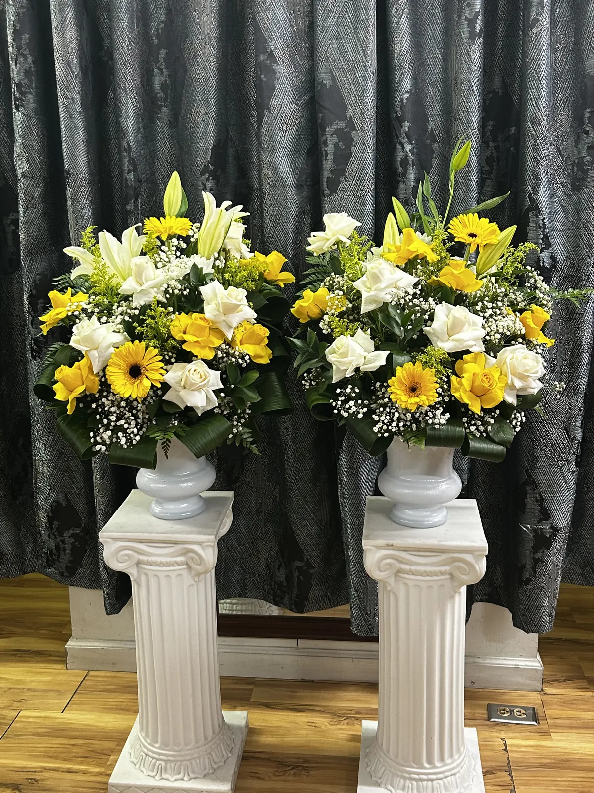 Matching yellow and white urn arrangements on pedestals